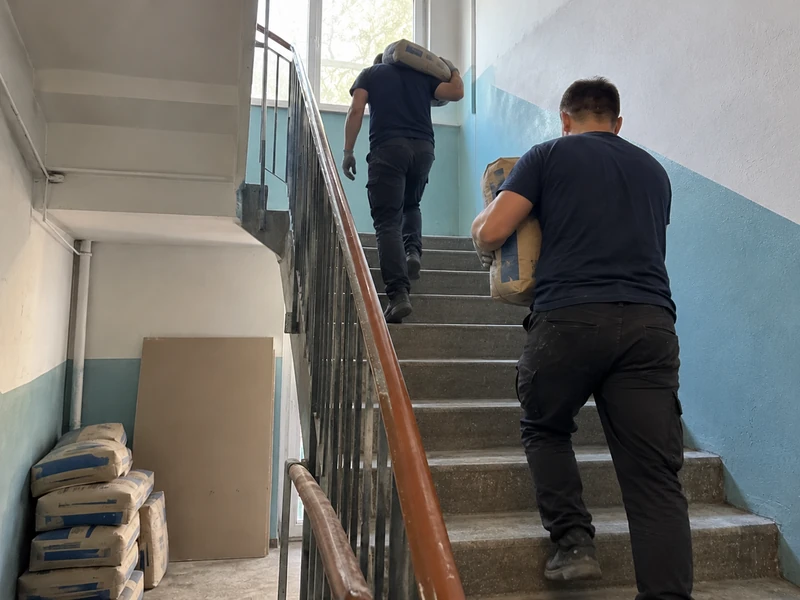 Грузчики заносят мешки со смесями на этаж по лестнице в Харькове
